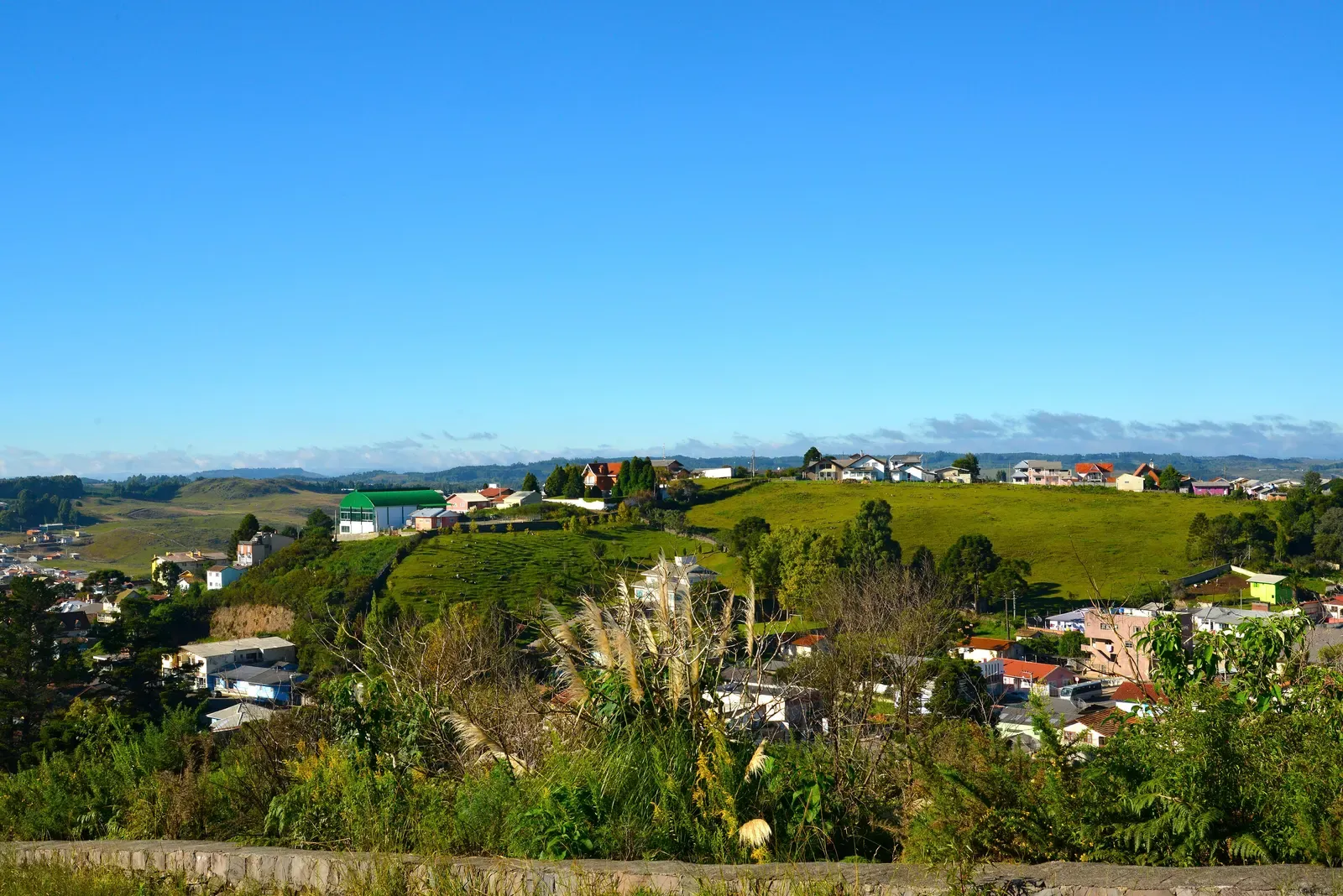 Vista do alto do Belvedere sobre as casas de São Joaquim e os campos em volta, com céu azul