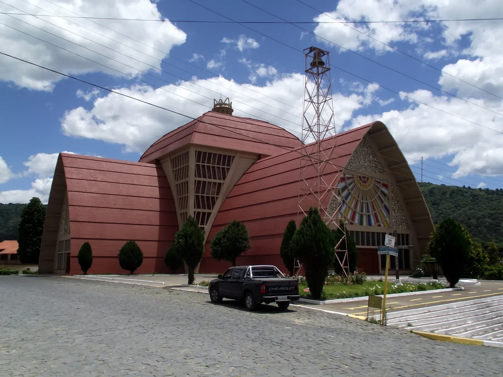 Igreja Matriz de Urubici, de telhado em forma de A e paredes vermelhas, com a praça em frente