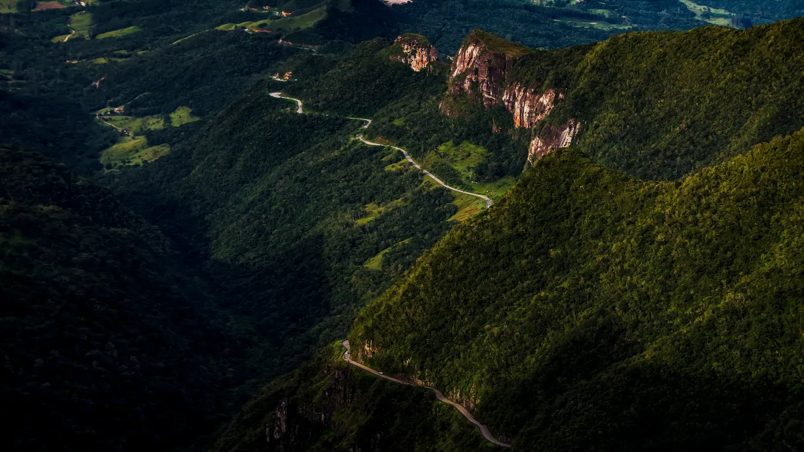 Curvas da Serra do Rio do Rastro descendo entre paredões e mata, vistas do alto